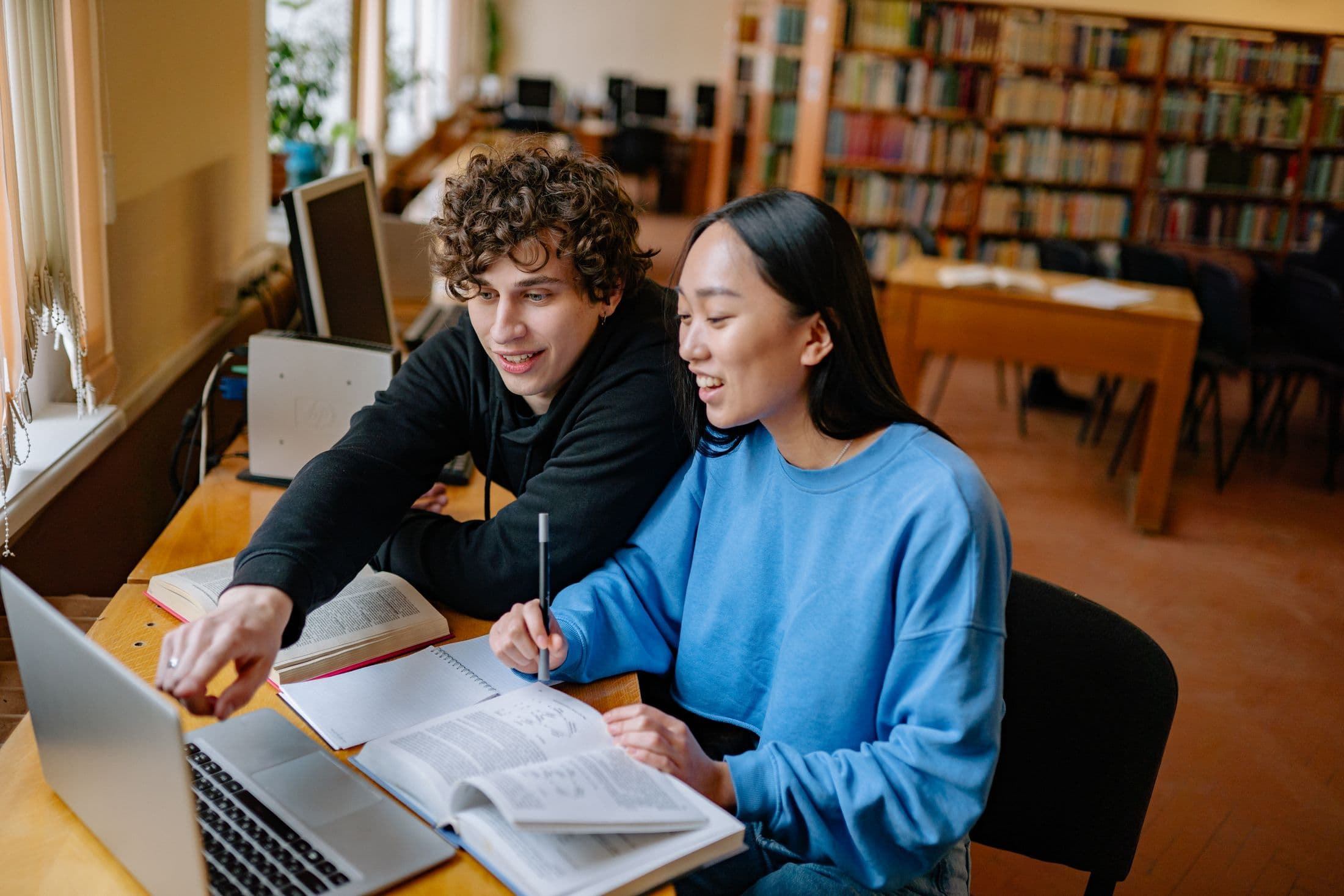 Two students discussing work together in a library